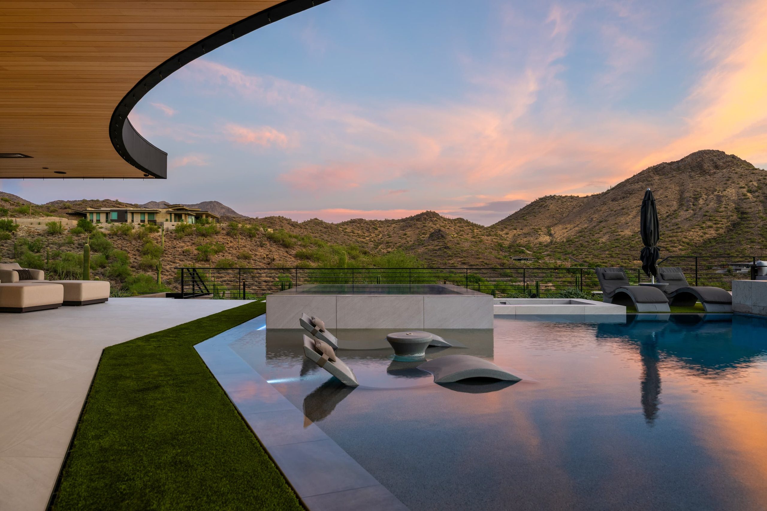 Sculpture on a raised spa edge, hillside pool and desert mountain beyond