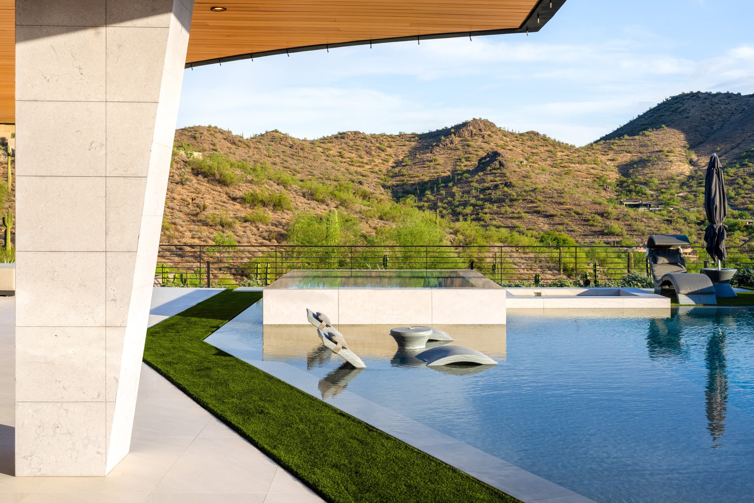 Cantilevered stone structure over a hillside pool at dusk